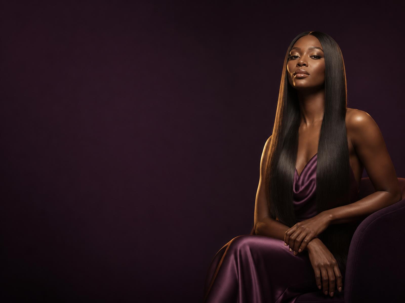 Model with long, glossy straight hair in deep plum and gold studio light